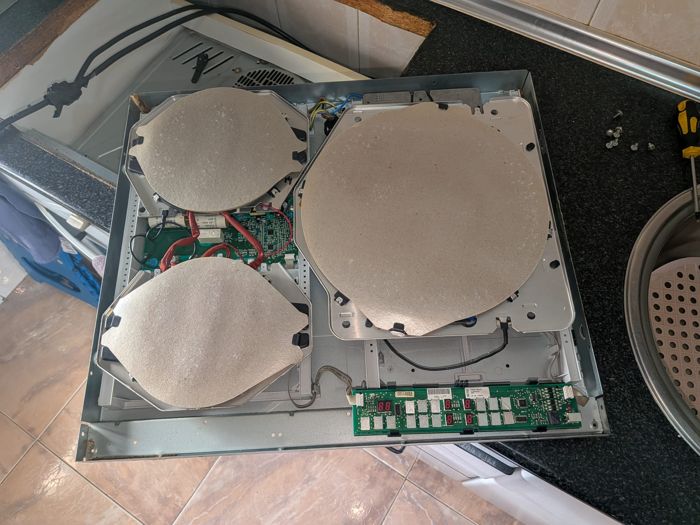 Placa de inducción desmontada durante una reparación a domicilio de CET Reparaciones